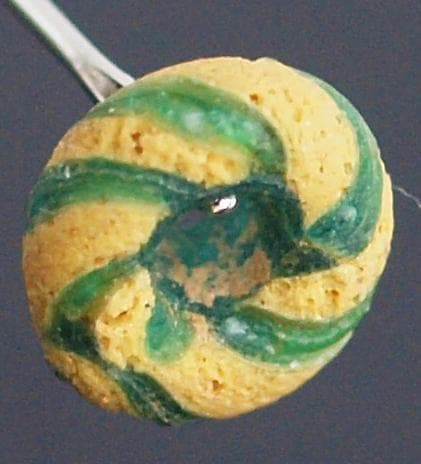 クリアな青緑に鮮やか黄で、回転する輪状モチーフを描くモザイク平玉　前後～6C頃の