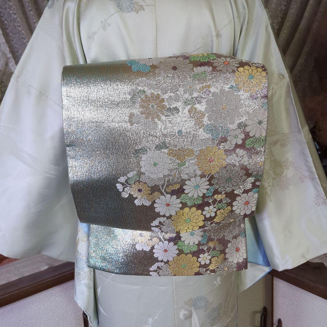 虹色に煌めくシルバーの地に、菊の花が艶やかに咲く、美しい正絹袋帯です