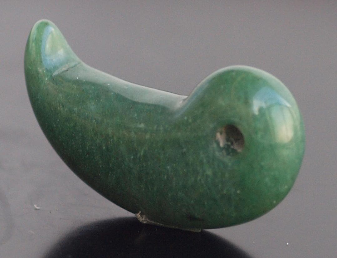 光にかざすと薄緑の細い帯状紋が出現、頭・胴の間には沈線、ずんぐり形の勾玉　沖縄の