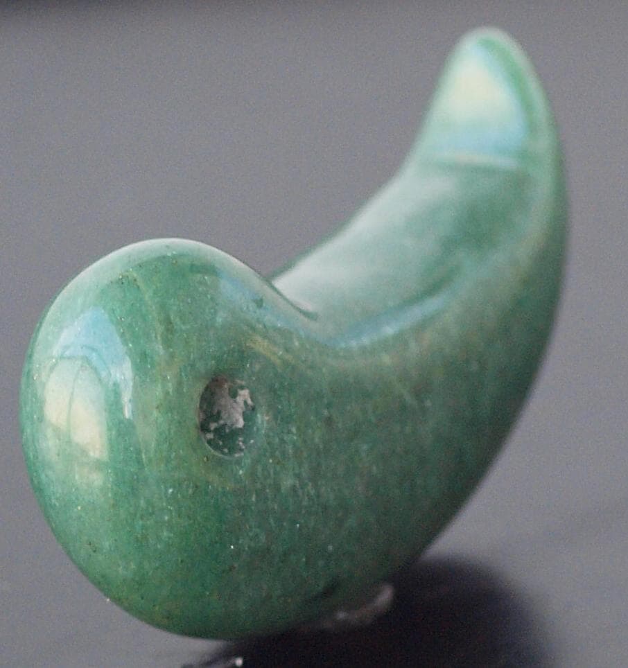 光にかざすと薄緑の細い帯状紋が出現、頭・胴の間には沈線、ずんぐり形の勾玉　沖縄の