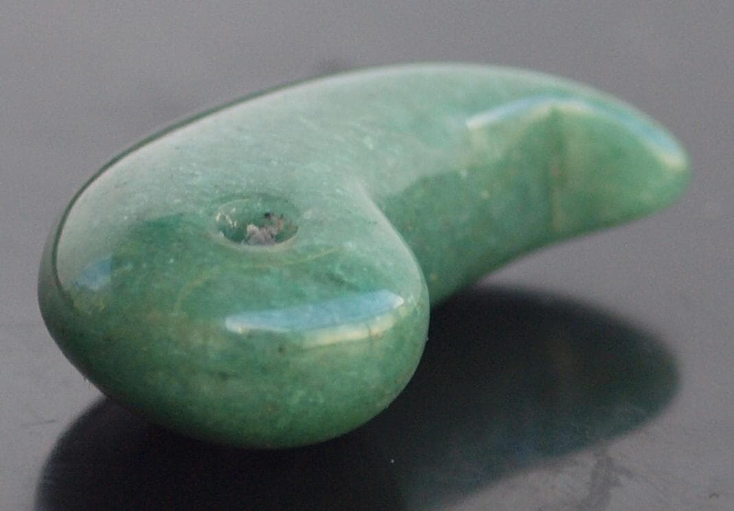 光にかざすと薄緑の細い帯状紋が出現、頭・胴の間には沈線、ずんぐり形の勾玉　沖縄の